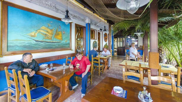 A restaurant with wooden tables and chairs, a large mural of a sailing ship, and hanging lights. - Palma Rooms B&B (Split)