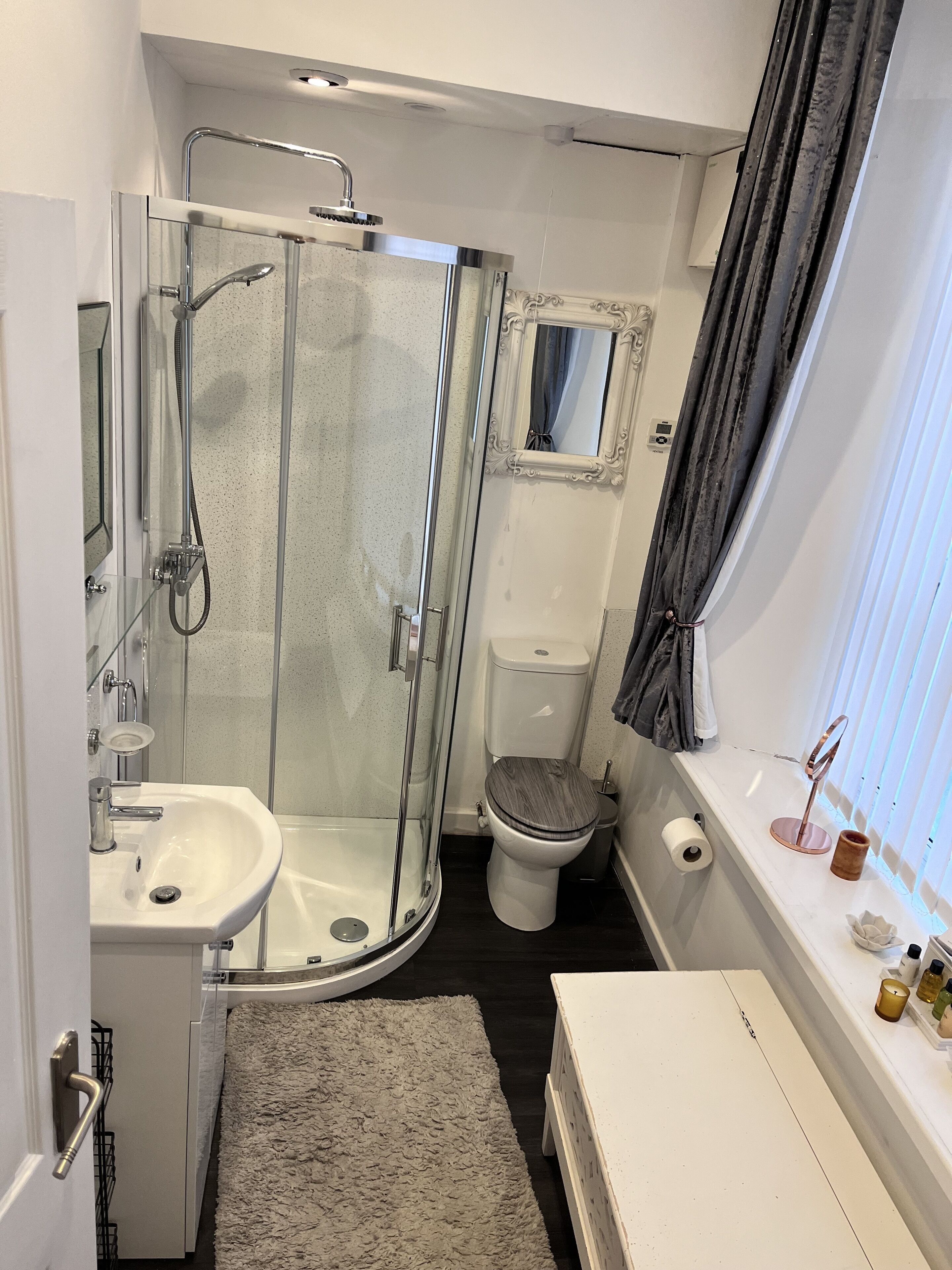 A compact bathroom with a glass-enclosed shower, a toilet, and a sink.