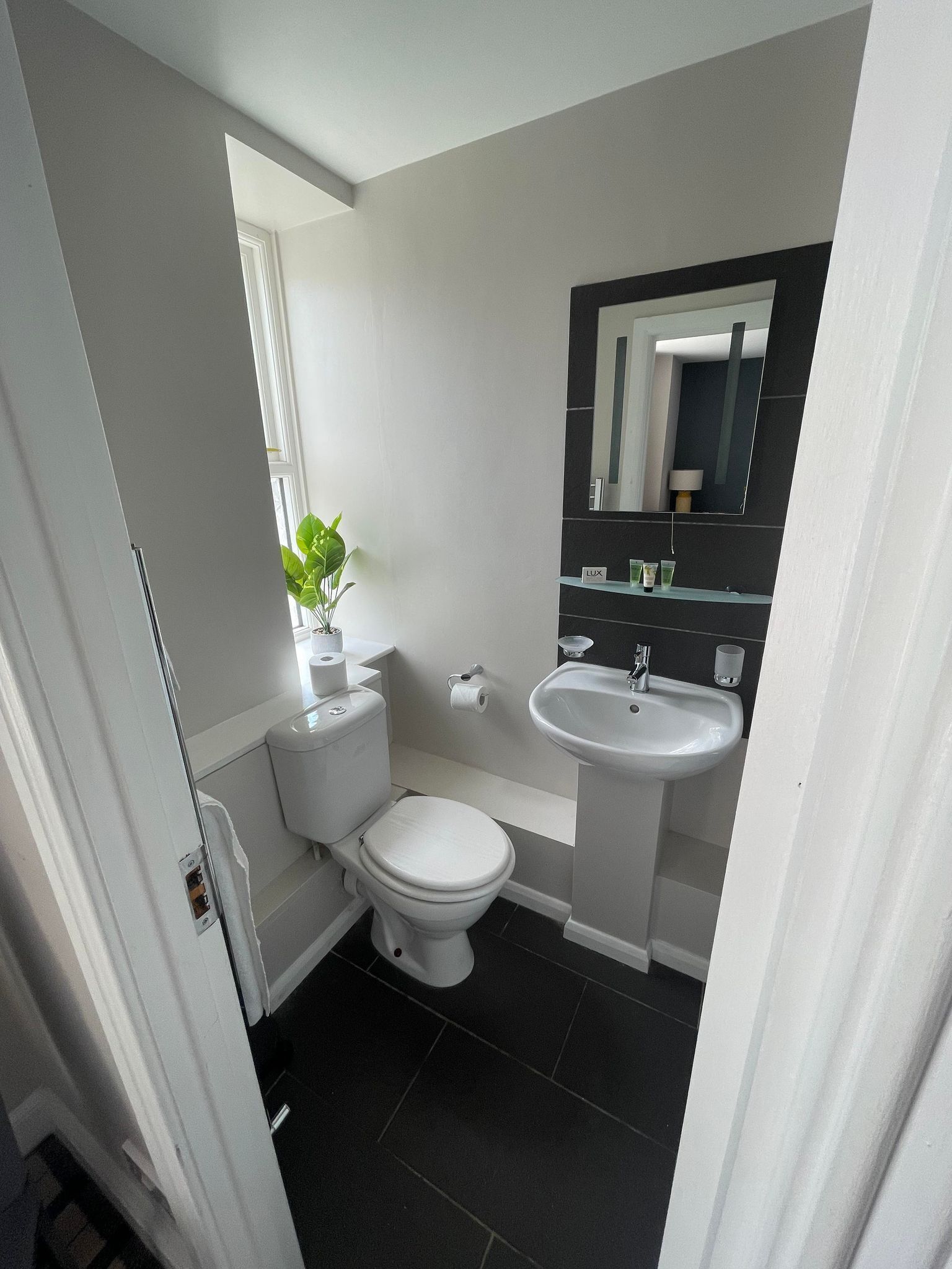 A small bathroom with a toilet, sink, and mirror.