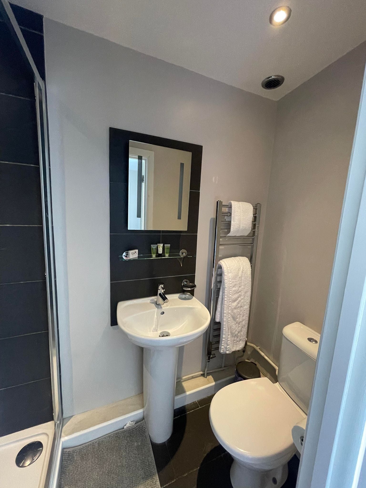 A bathroom with a white sink, a mirror, a toilet, and a towel rack.