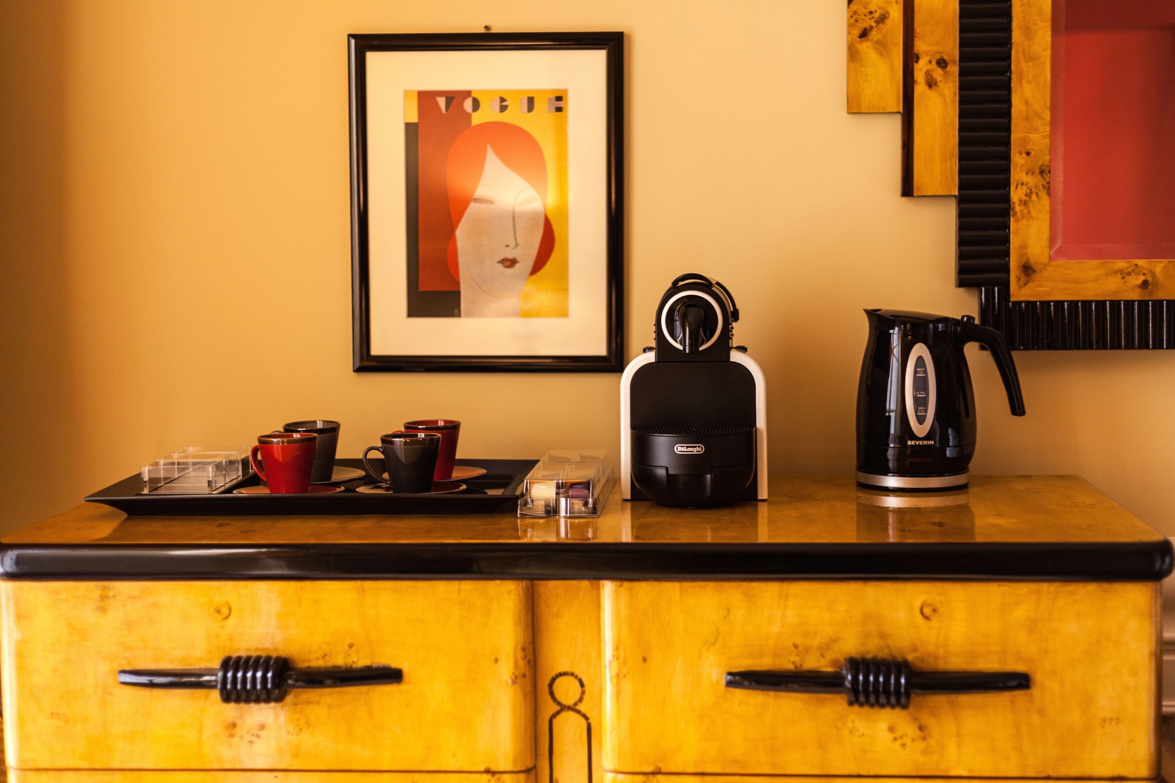 Une petite cuisine équipée d’une machine à café, d’une bouilloire et d’un plateau avec des tasses et une théière.