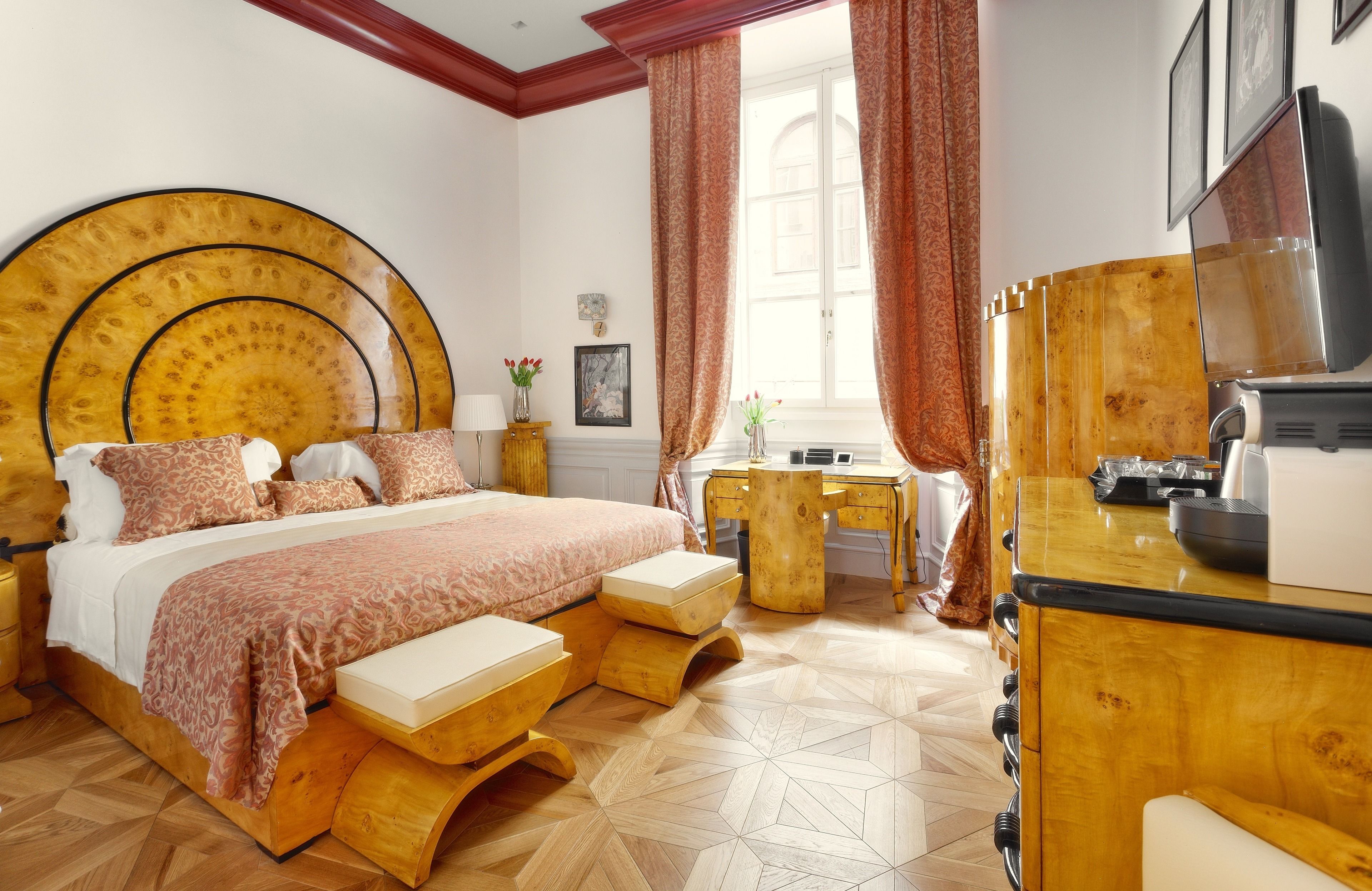 A bedroom with a large bed, wooden furniture, a desk, and a television.