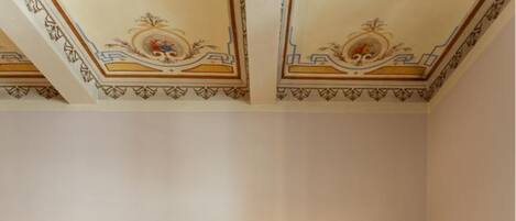 Una camera da letto con un letto, un divano, due comodini e un soffitto decorato.
