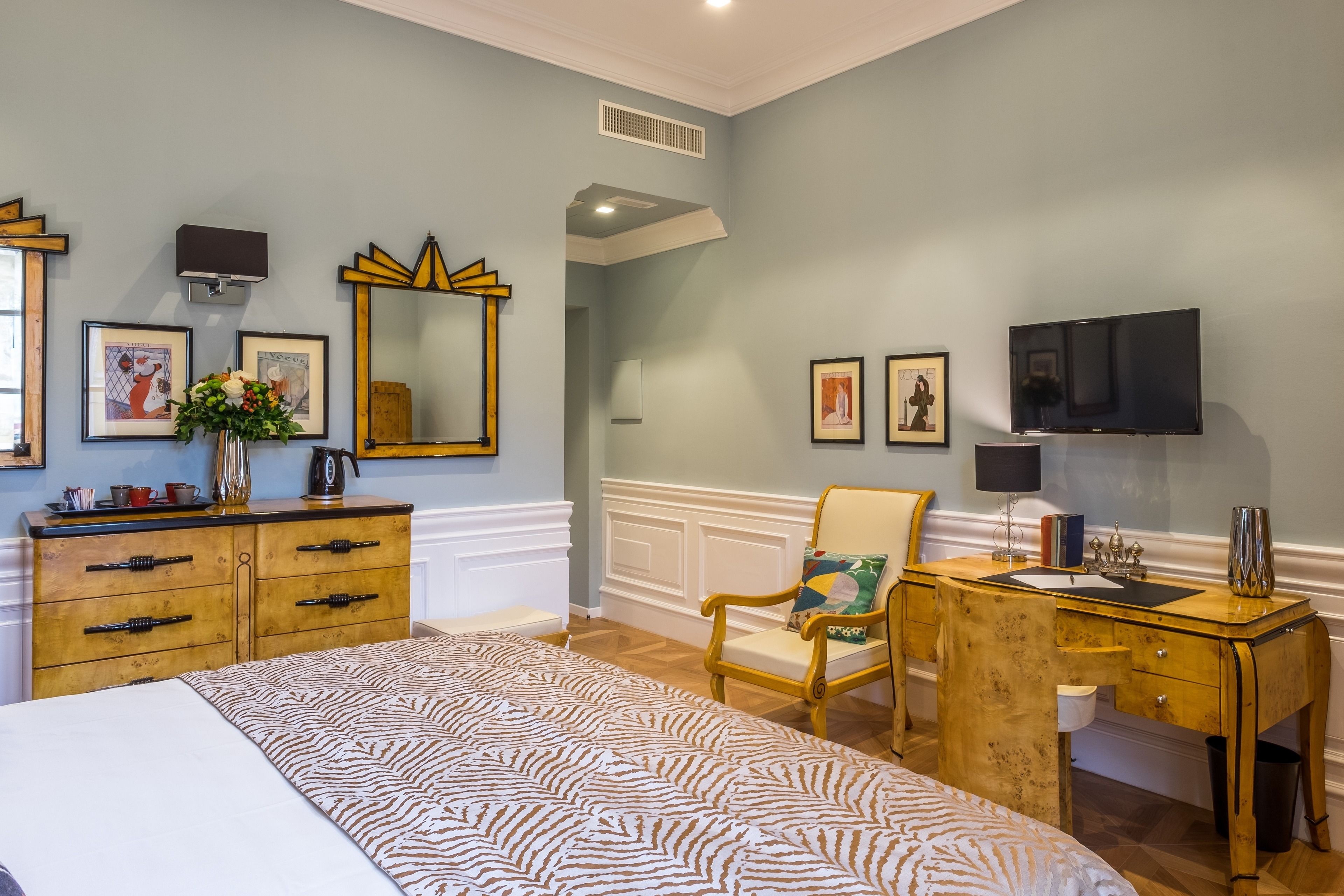 Une chambre à coucher comprenant un lit, une commode en bois, un bureau, une chaise et un téléviseur.