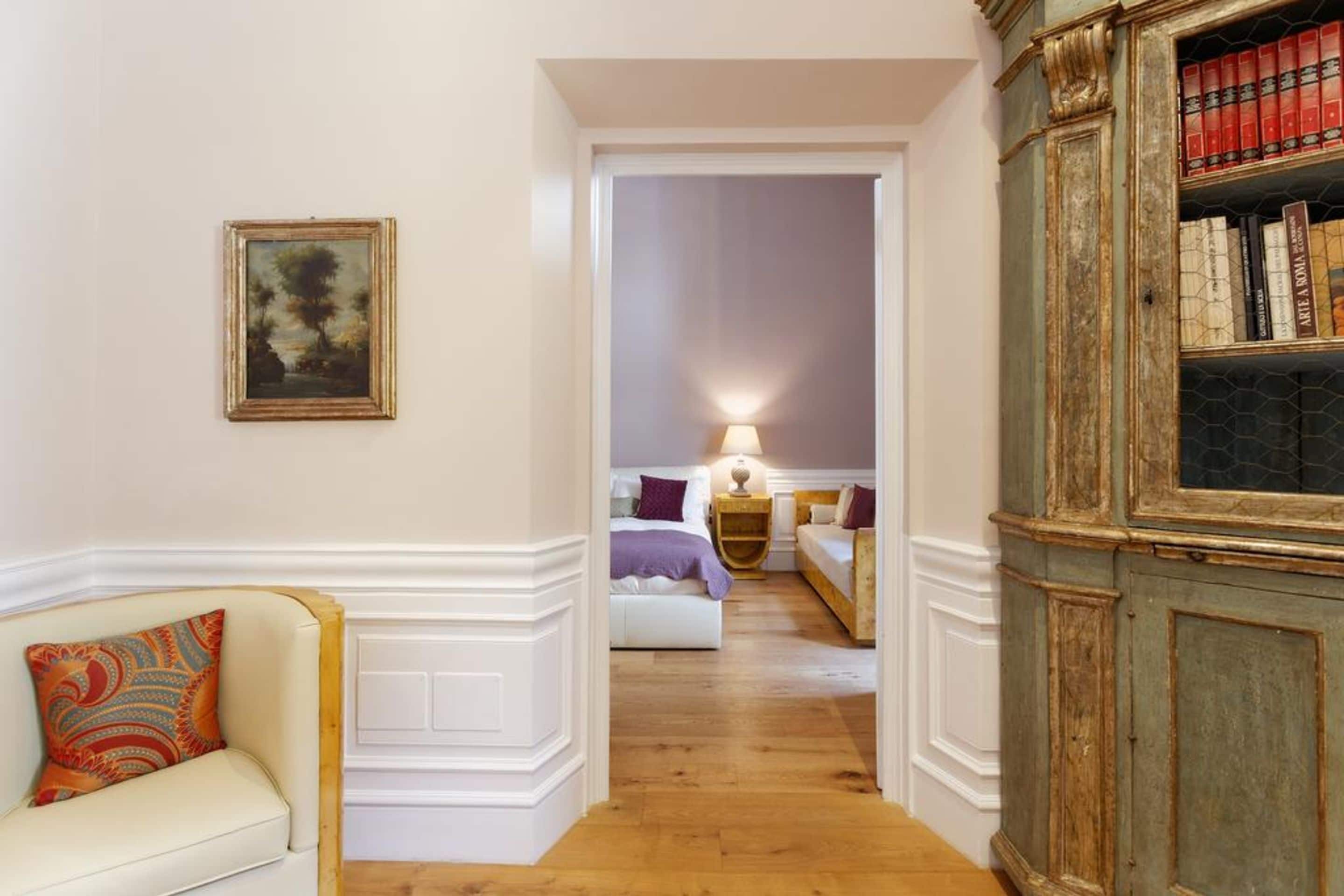 A hallway with a white sofa, a painting, and a bookshelf.