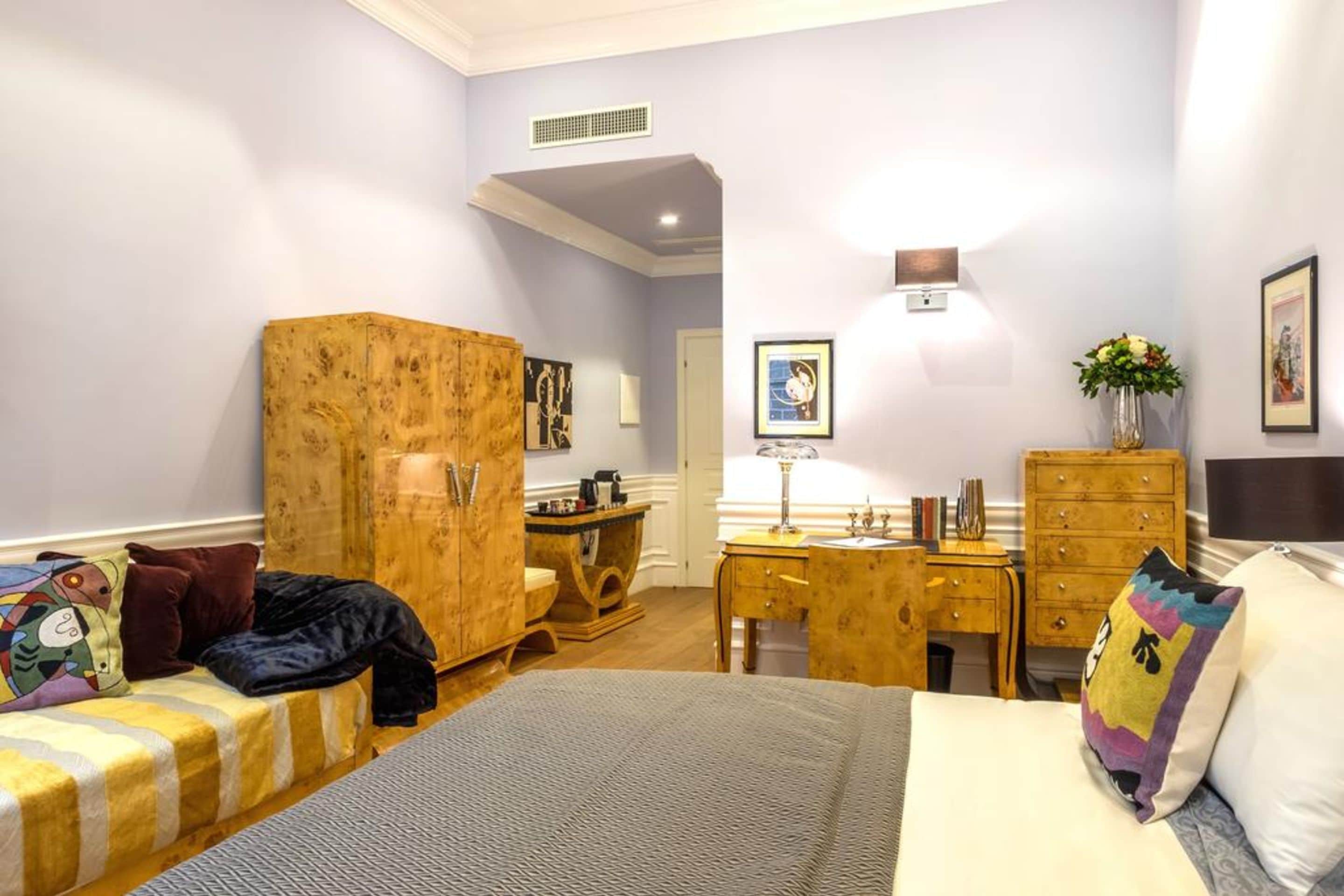 A bedroom with a bed, a wooden wardrobe, a desk, a dresser, and a bathroom.