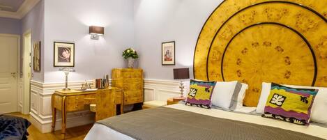Een slaapkamer met een groot bed, een houten dressoir, een bureau en een wandlamp.