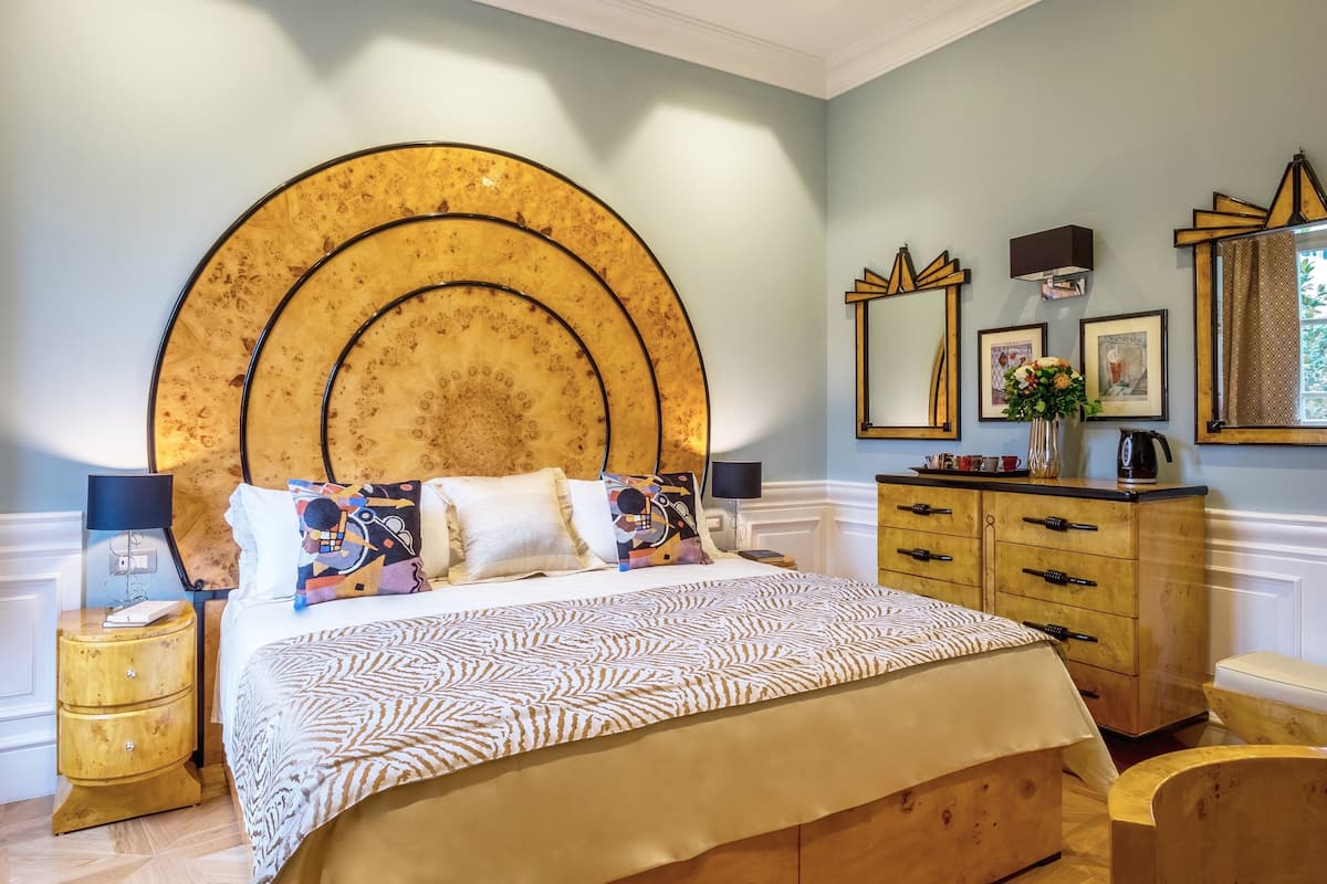 A bedroom with a large bed, a wooden dresser, and a nightstand.