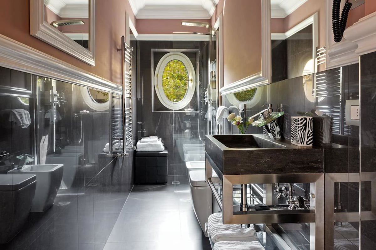 A modern bathroom with a large mirror, a central sink, and a glass-enclosed shower area.