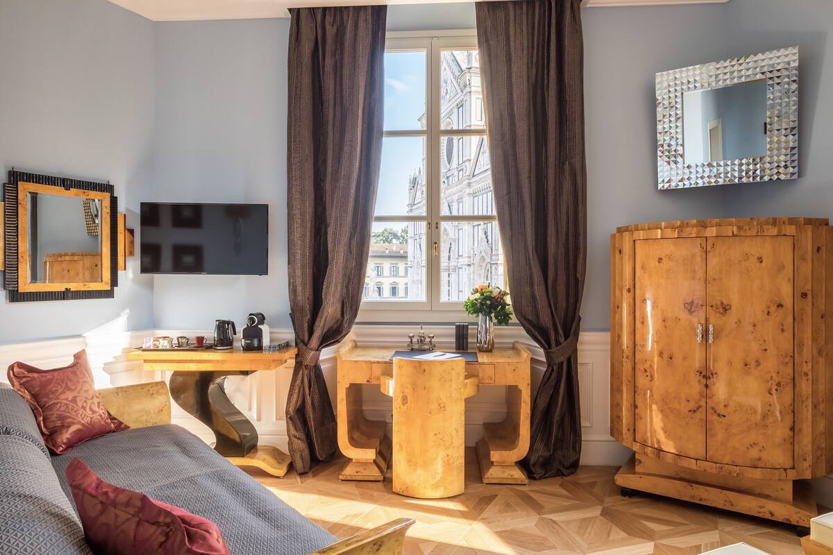 A room with a wooden desk, a television, a large mirror, and a wardrobe.
