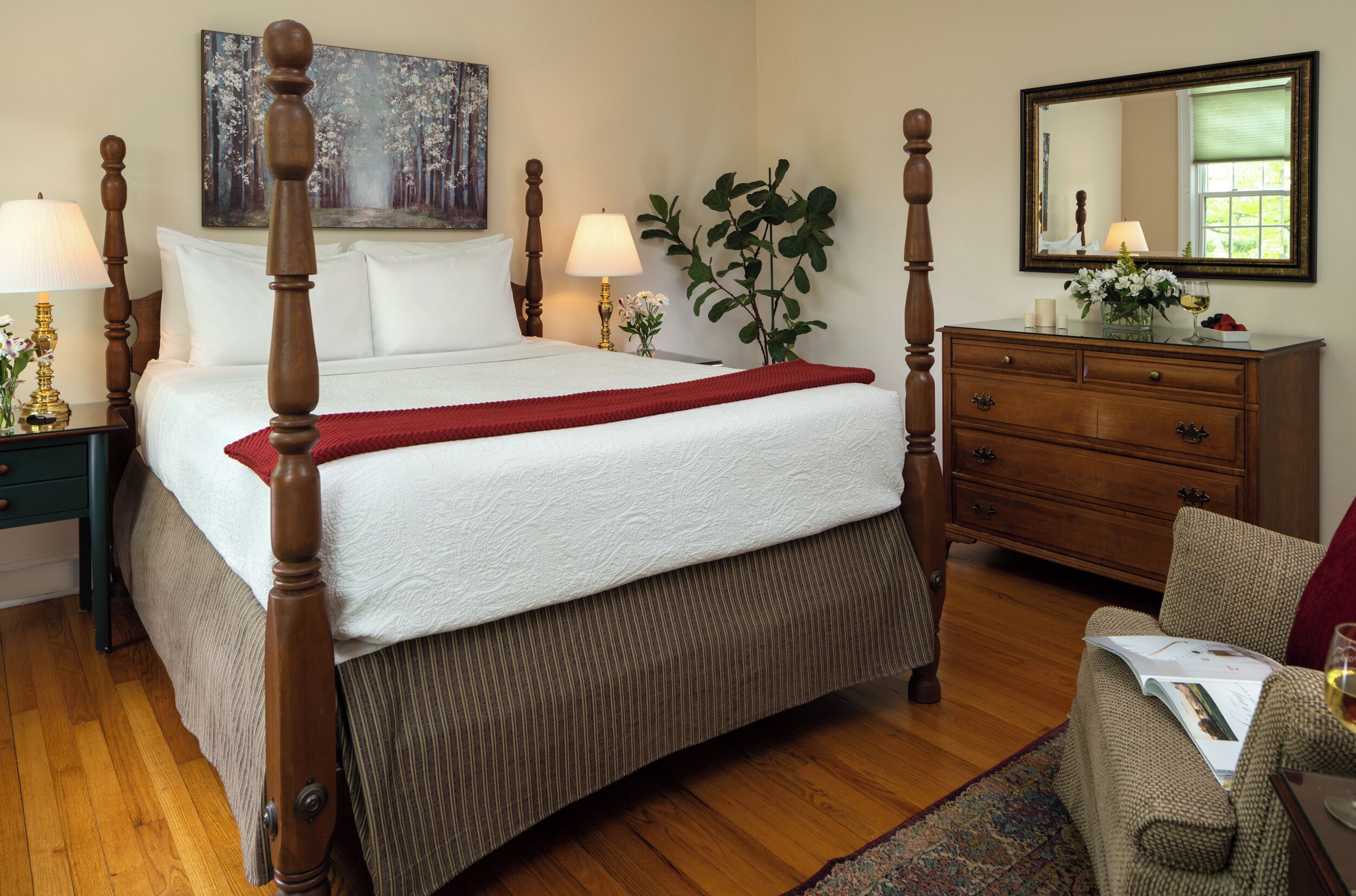 Une chambre d’hôtel bien aménagée, avec un lit à baldaquin, une commode, un miroir et un tableau accroché au mur.