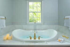 A bathroom with a large bathtub, a window, and a towel rack.