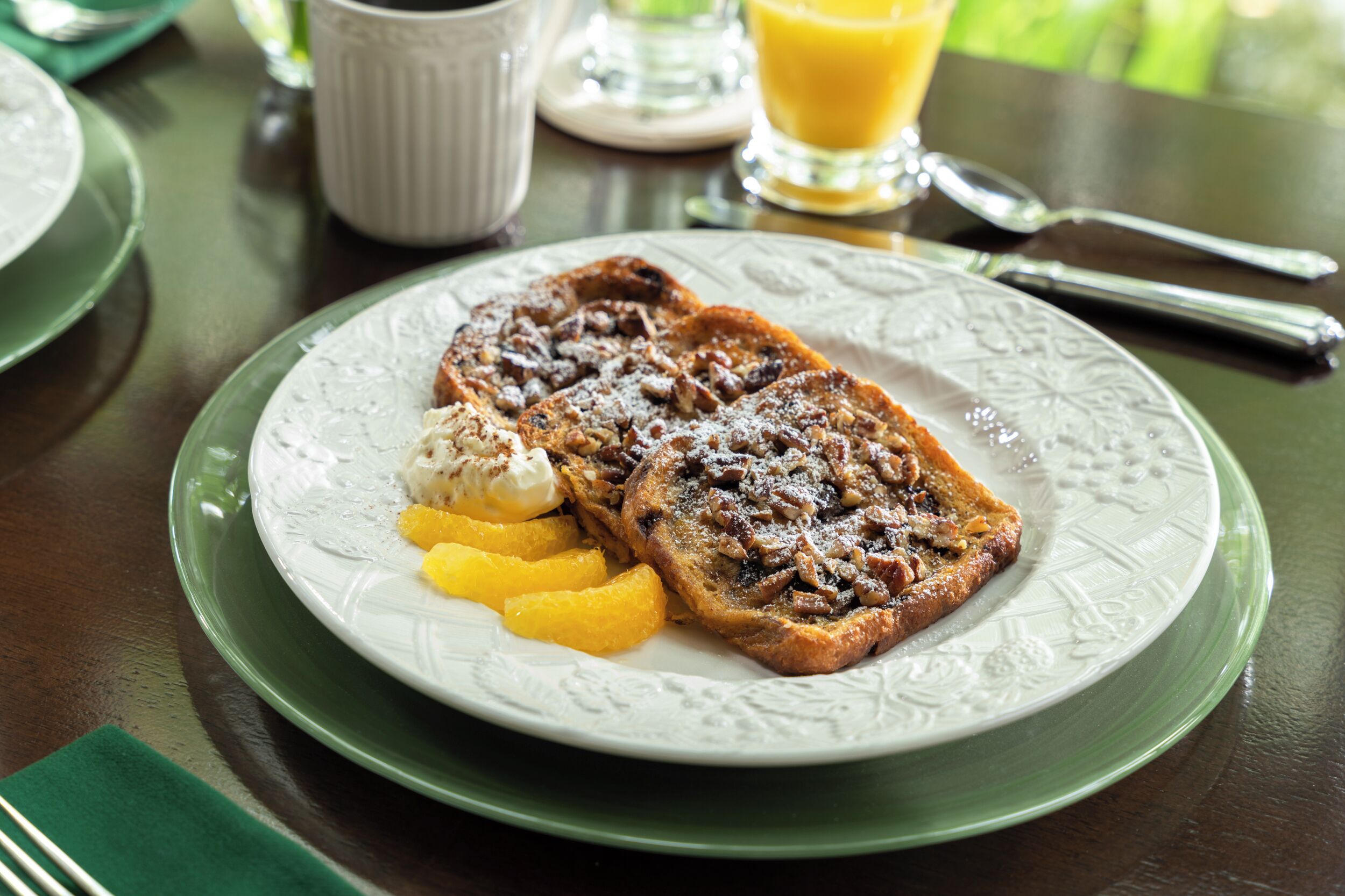 A breakfast plate with French toast, a scoop of ice cream, and a slice of orange.