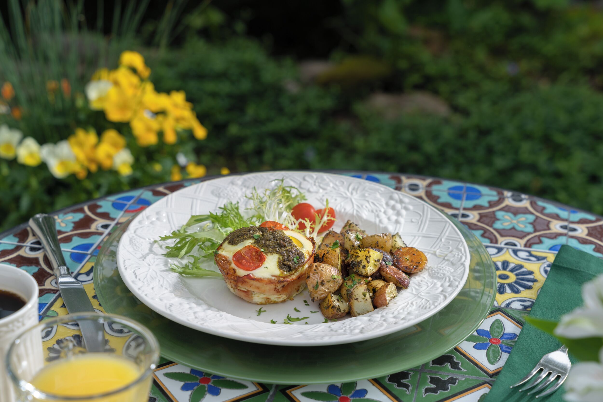 Une assiette de nourriture comprenant une salade, un œuf poché et des pommes de terre rôties, le tout disposé sur une nappe aux couleurs vives.