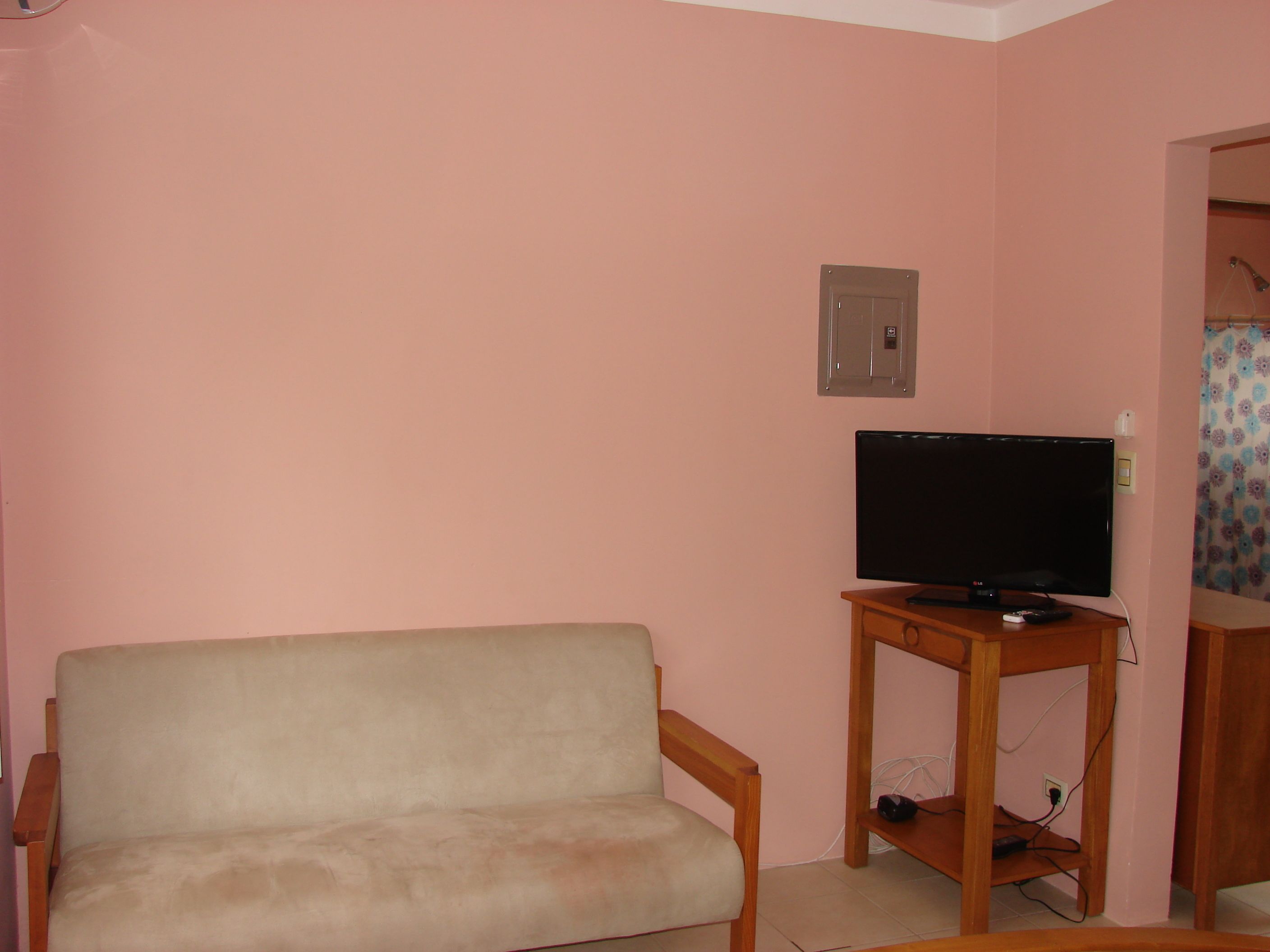 A living room with a beige sofa, a wooden TV stand, and a television.