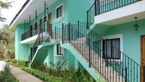 Ein türkisfarbenes, zweistöckiges Haus mit Treppe, Balkon und Garten.