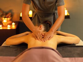 A massage therapy session in a spa setting with a massage table, candles, and a dimly lit ambiance.