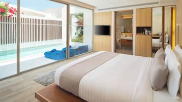 Una habitación de hotel moderna con una cama grande, un televisor, un baño con lavabo y espejo, y un balcón con piscina y sillas azules.