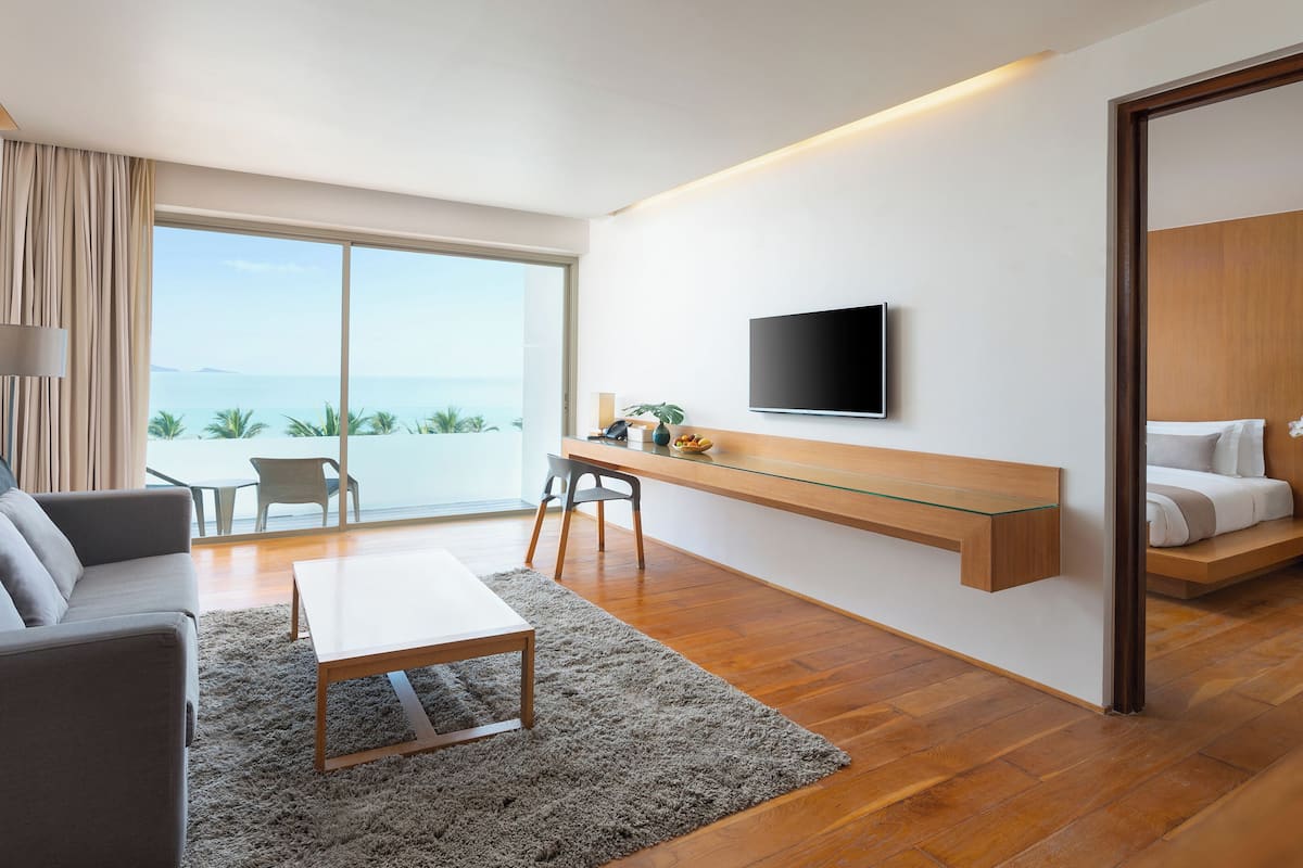 Una habitación de hotel moderna con un ventanal grande, un televisor de pantalla plana, un sofá, un escritorio y una cama.