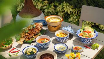 A table with various dishes, including a whole fish, bowls of soup, and a salad.