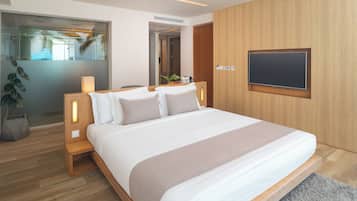 Una habitación de hotel moderna con una cama grande, cabecera de madera, lámparas de noche, un televisor de pantalla plana montado en la pared y vista a palmeras a través de la ventana.