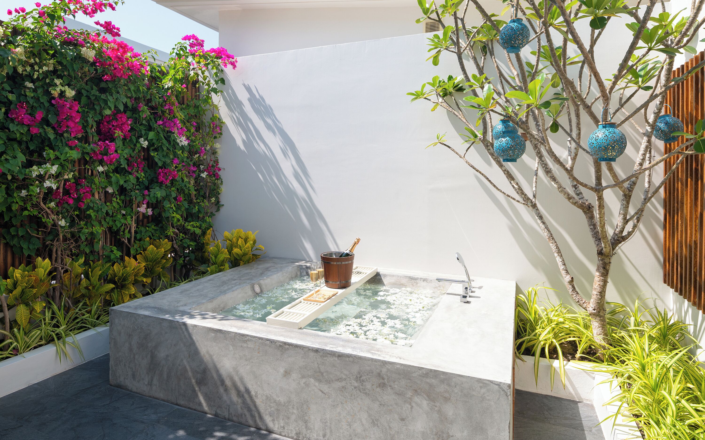 A spa area with a hot tub, surrounded by lush greenery and decorative blue lanterns.