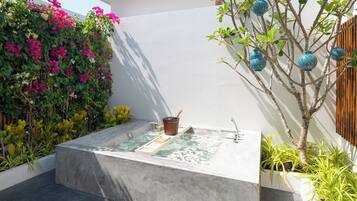 A spa area with a hot tub, surrounded by lush greenery and decorative blue lanterns.