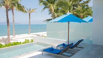 A poolside area with lounge chairs and umbrellas, overlooking the sea.
