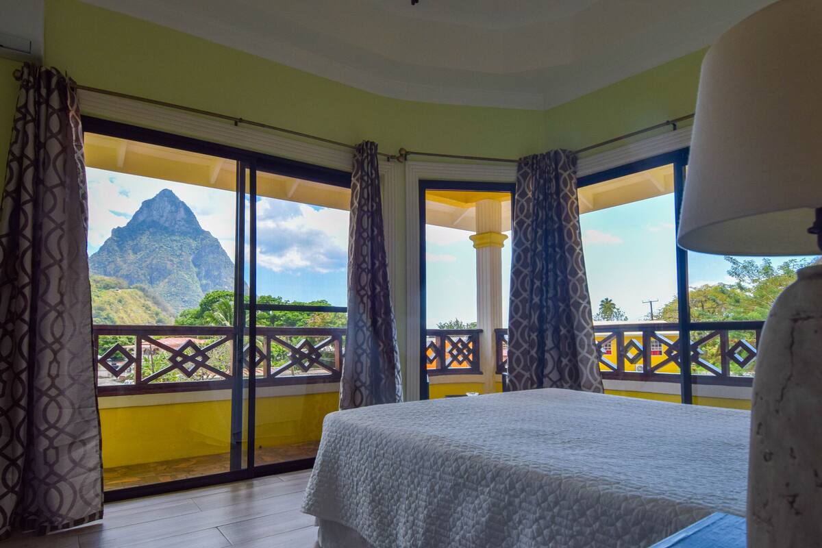 Una camera da letto con un letto, un balcone vista montagna e una lampada.
