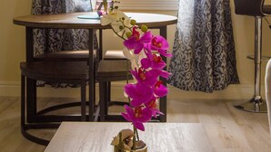 A dining area with a table, chairs, and a vase with flowers. - Sea Piton View Apartment (Soufrière)
