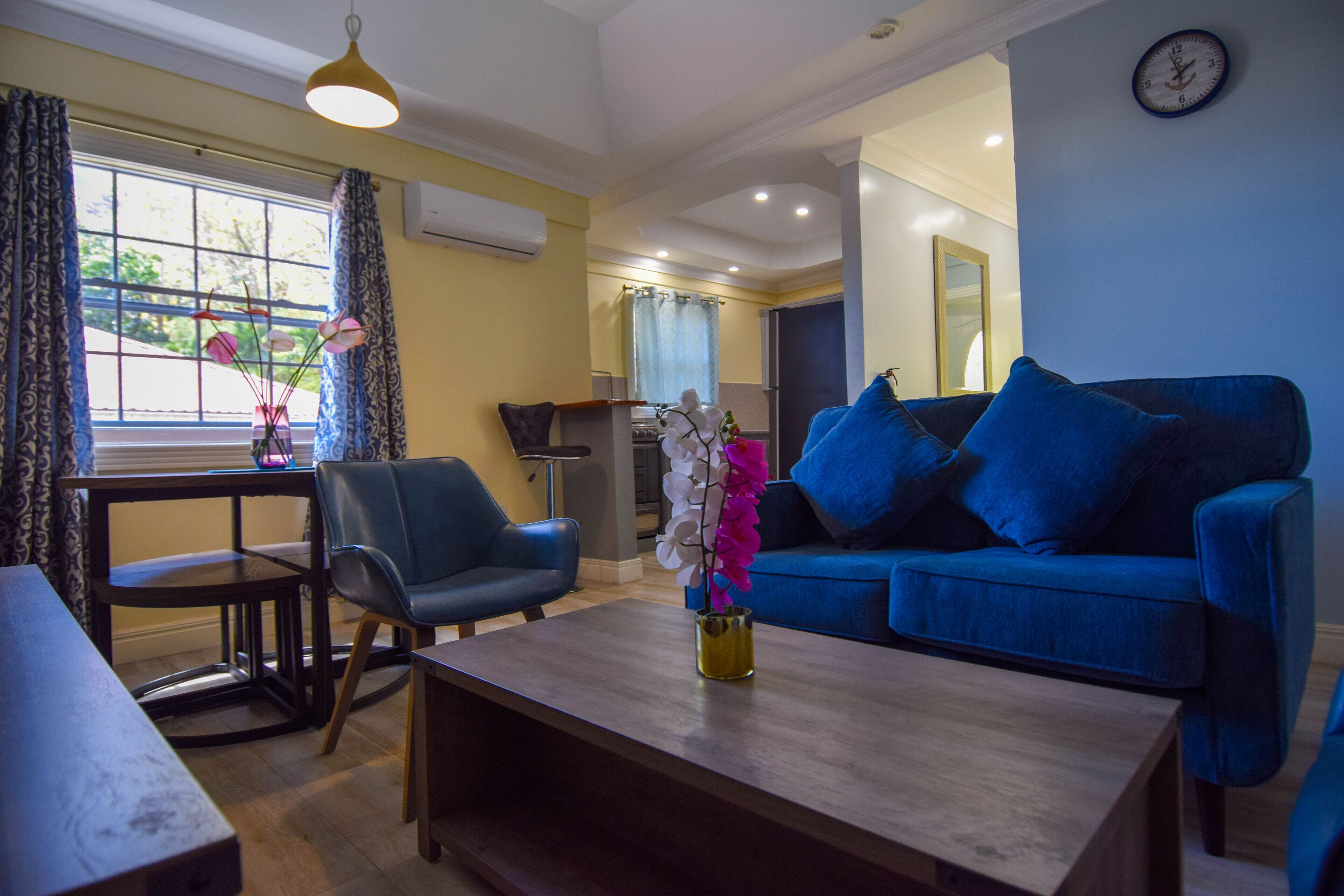A living room with a blue sofa, a coffee table, a chair, and a vase with flowers.