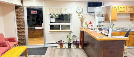 Ein kompakter Wohnraum mit Küchenzeile, einem Essbereich mit rotem Sofa und Holztisch sowie einem kleinen Eingangsbereich mit geschlossener Tür.