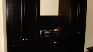 Guarda-roupa de madeira escura com várias gavetas e uma porta espelhada.