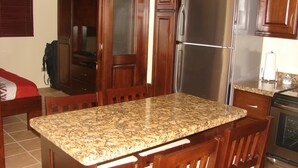 Cozinha com bancadas de granito, armários de madeira, geladeira de aço inoxidável e lava-louças.