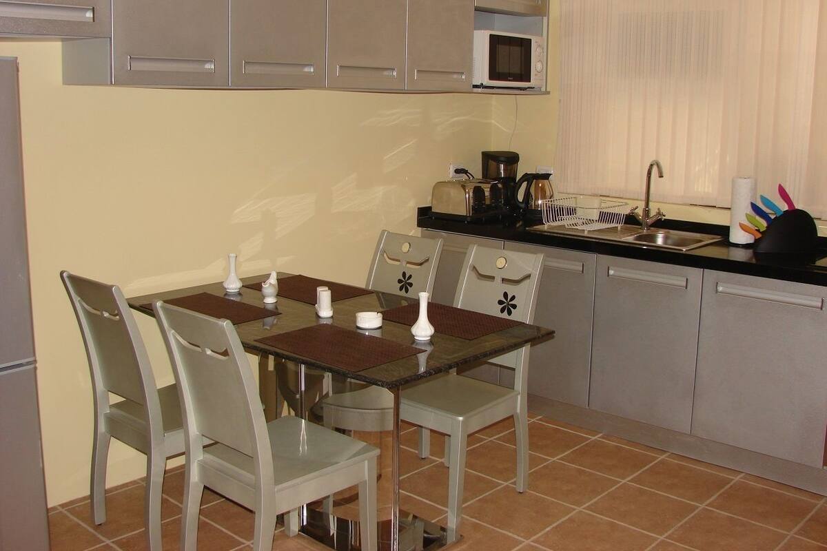 A compact kitchen with a dining table, chairs, a microwave, and a sink.