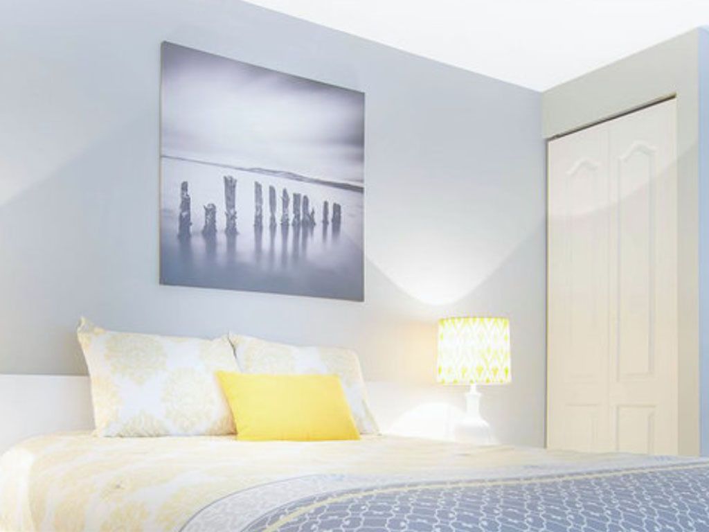 Un dormitorio con cama, mesita de noche, lámpara y una puerta.