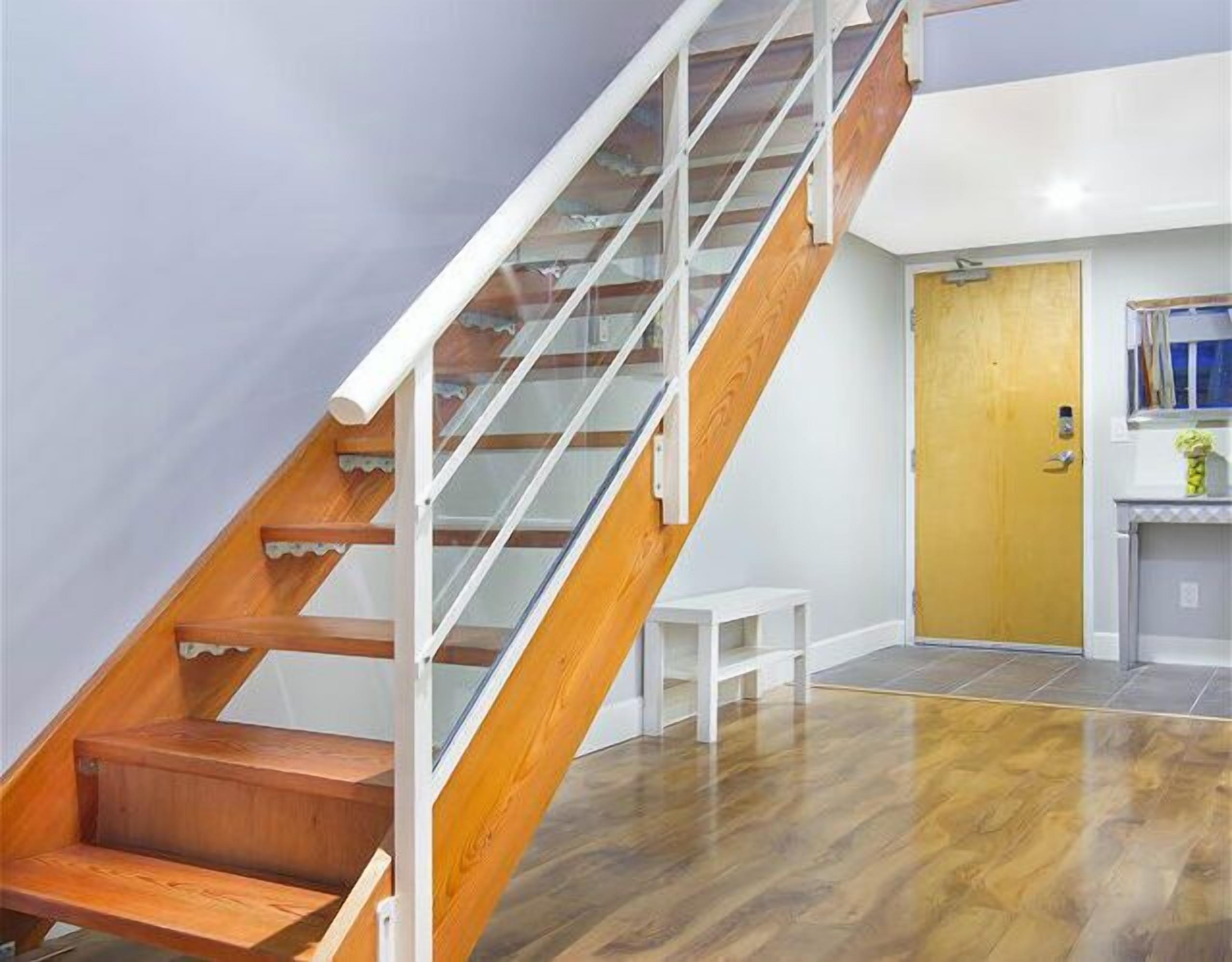 A staircase with wooden steps and glass railings leading to a landing.