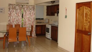 Una cocina compacta con zona de comedor, que incluye estufa, fregadero y sillas.