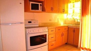 Una cocina equipada con refrigerador, microondas, horno y armarios de madera.