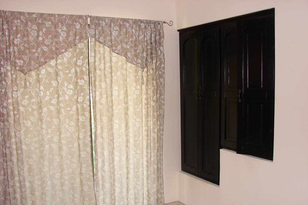 A room with a large window, a door, and a curtain.