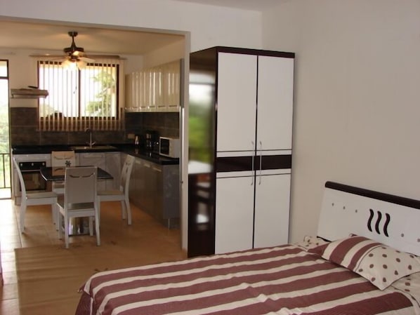A compact room with a bed, a kitchenette, and a dining area.