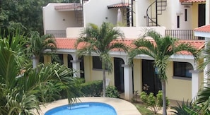 A building with multiple balconies, a swimming pool, and lush greenery.