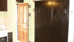 A kitchen with a wooden door, a white oven, and a dark wooden cabinet. - Las Torres Studio (Sardinal)