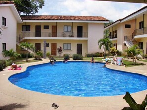A swimming pool surrounded by a building with balconies and a tiled roof. - Las Torres Studio (Sardinal)