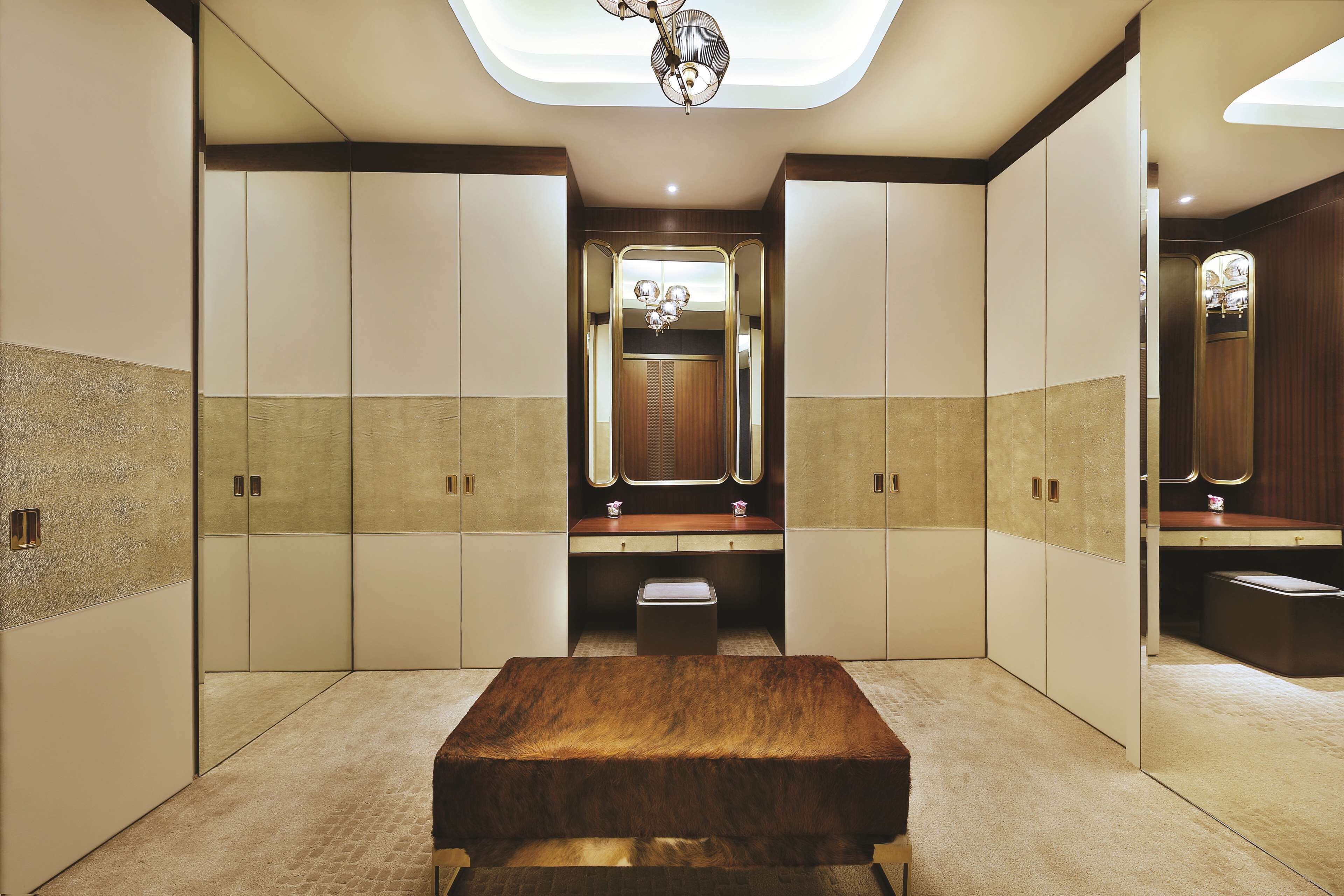 A modern bathroom with a large mirror, wooden vanity, and a bench.