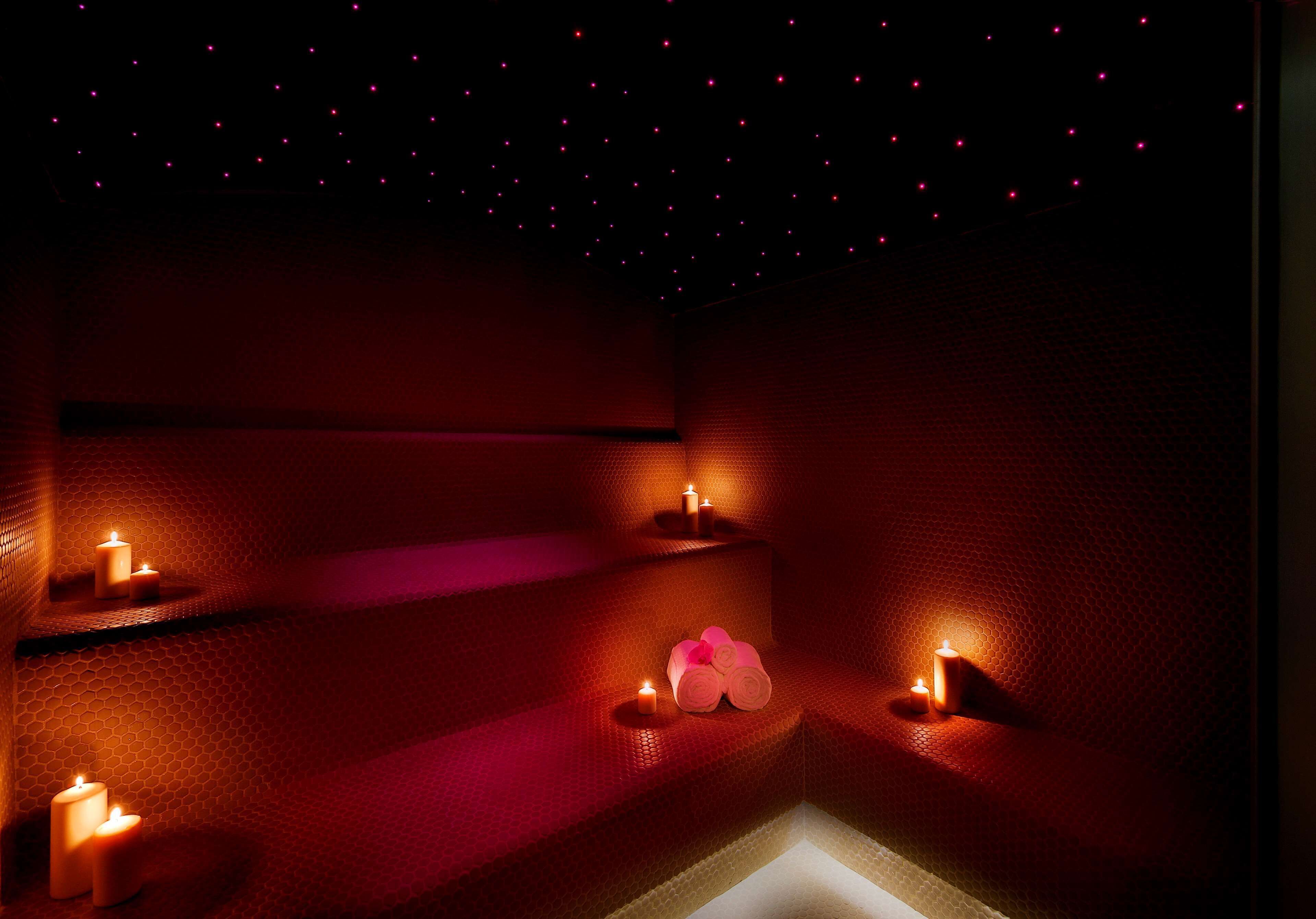 A dimly lit room with a textured wall, a small seating area with candles, and a starry ceiling.