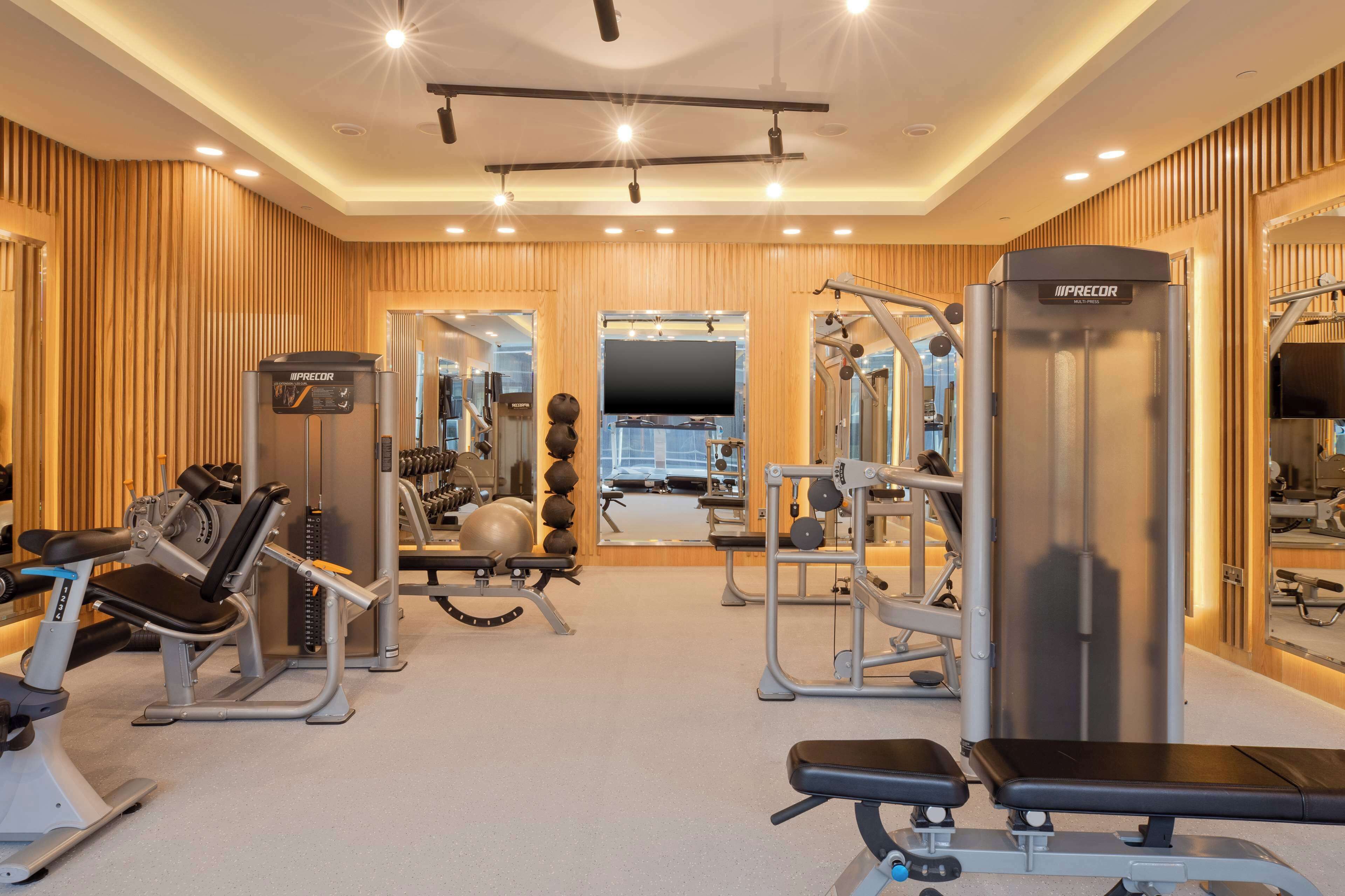 A gym with various exercise equipment, including a bench, weight machines, and a mirror.