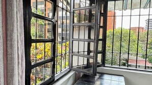 Une pièce d’angle avec une étagère en métal noir, une petite poubelle et un tapis à motifs.