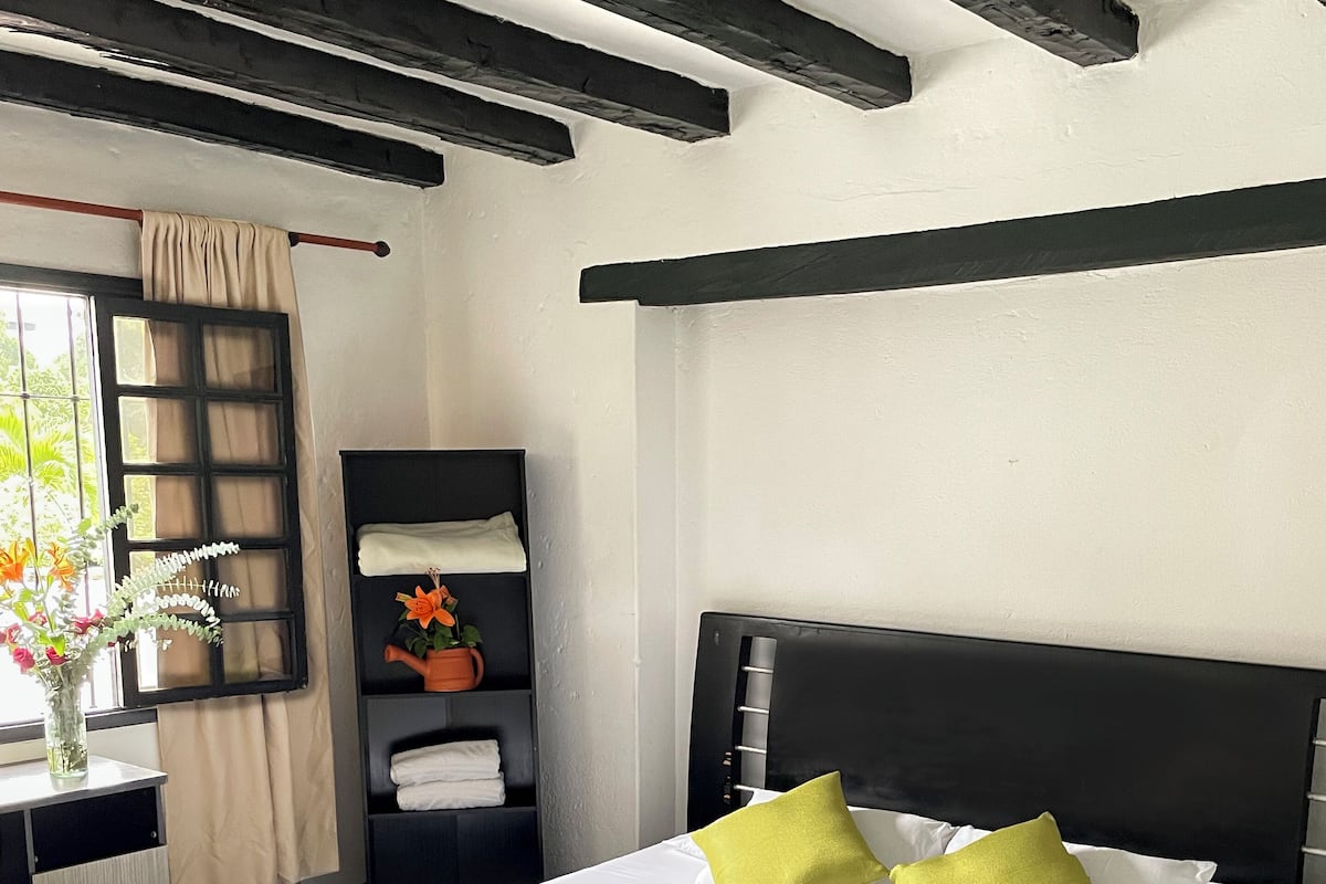 Une chambre d’hôtel moderne avec un grand lit, une table de chevet, une armoire et une fenêtre avec des rideaux.
