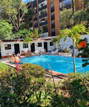 Una piscina al aire libre, sillones reclinables de piscina